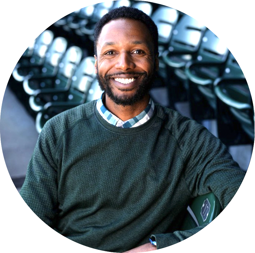 Darell Stewart EMBA 2022 - man smiling, with beard, wearing green sweater, sitting in auditorium 